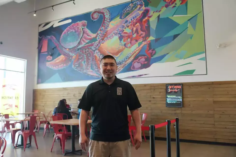 Harold Wong in the Boiling Dragon dining room, in front of the octopus mural